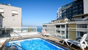 Ein Pool auf dem Dach mit Blick auf das Meer, umgeben von Gebäuden.