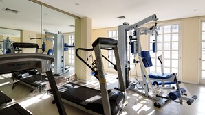 Ein Fitnessraum mit Trainingsgeräten, darunter Laufband und Kraftgeräte.