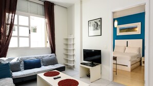 Ein modernes Wohnzimmer mit Sofa, Couchtisch, Fernseher und ein Schlafzimmer mit Bett und Nachttisch.