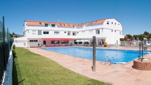 Un hotel con piscina, un patio techado y una zona junto a la piscina con ladrillo.