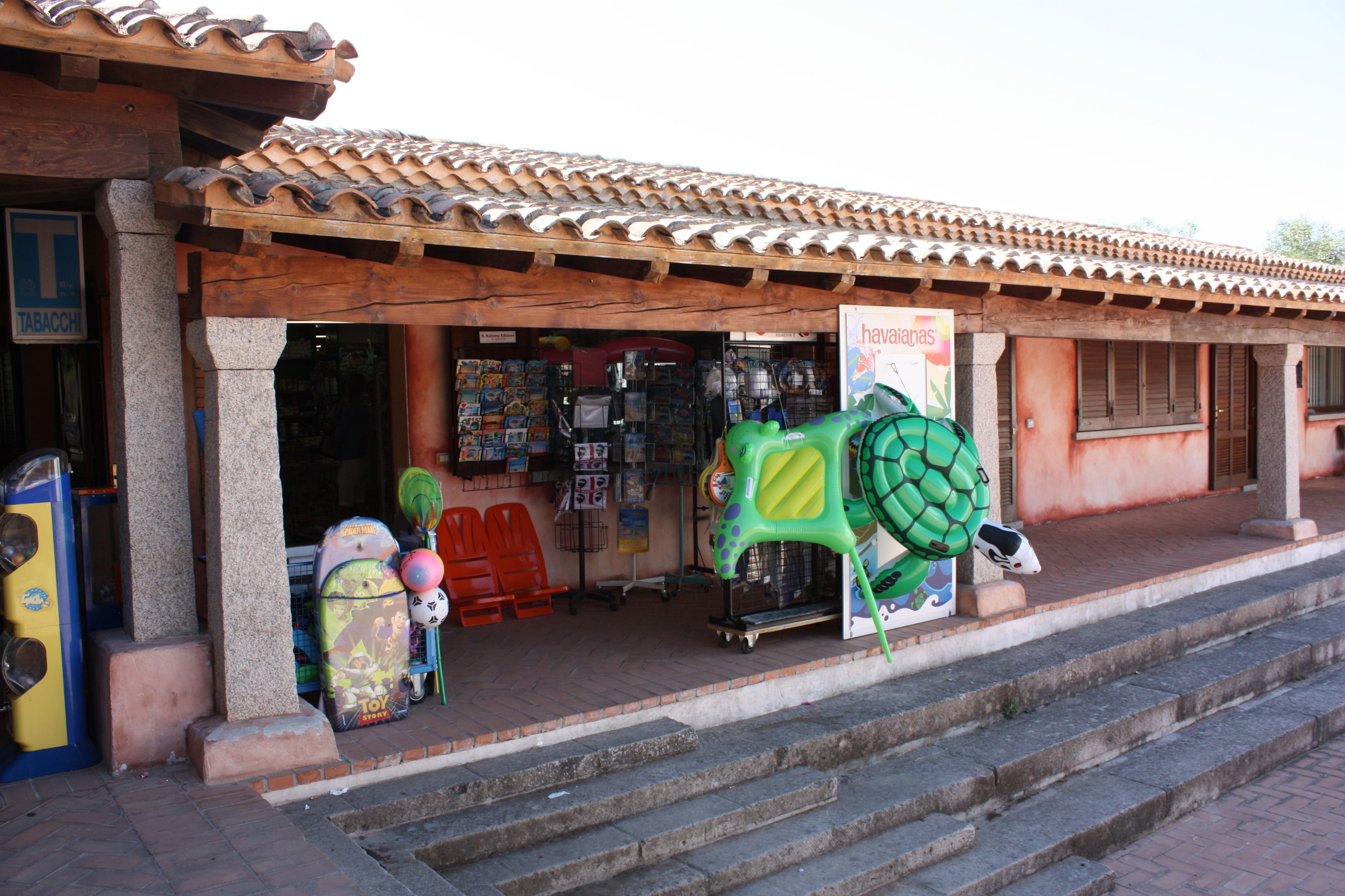A storefront with a tiled roof, a signboard, and various items displayed outside.