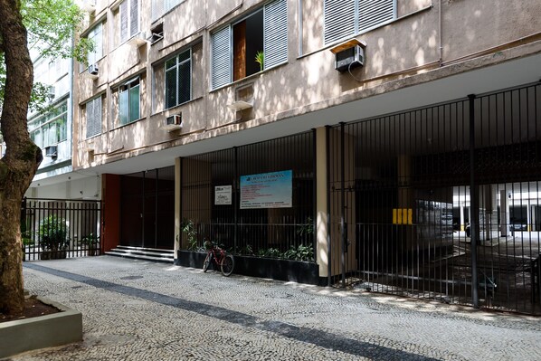 A building with a gated entrance, a bicycle parked outside, and a signboard.