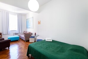 A room with a bed, a sofa, a small table, and a window with curtains. - Omar do Rio - SL906 (Rio de Janeiro)