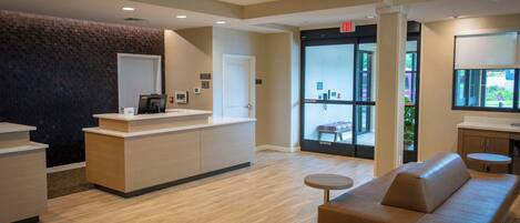 A reception area with a reception desk, a waiting area with a sofa, and a glass door leading outside.