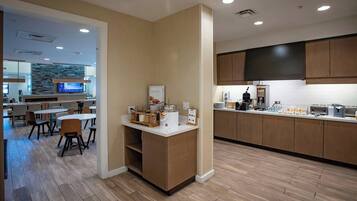 A modern kitchen with wooden cabinets, a central island, and a dining area with chairs and tables.