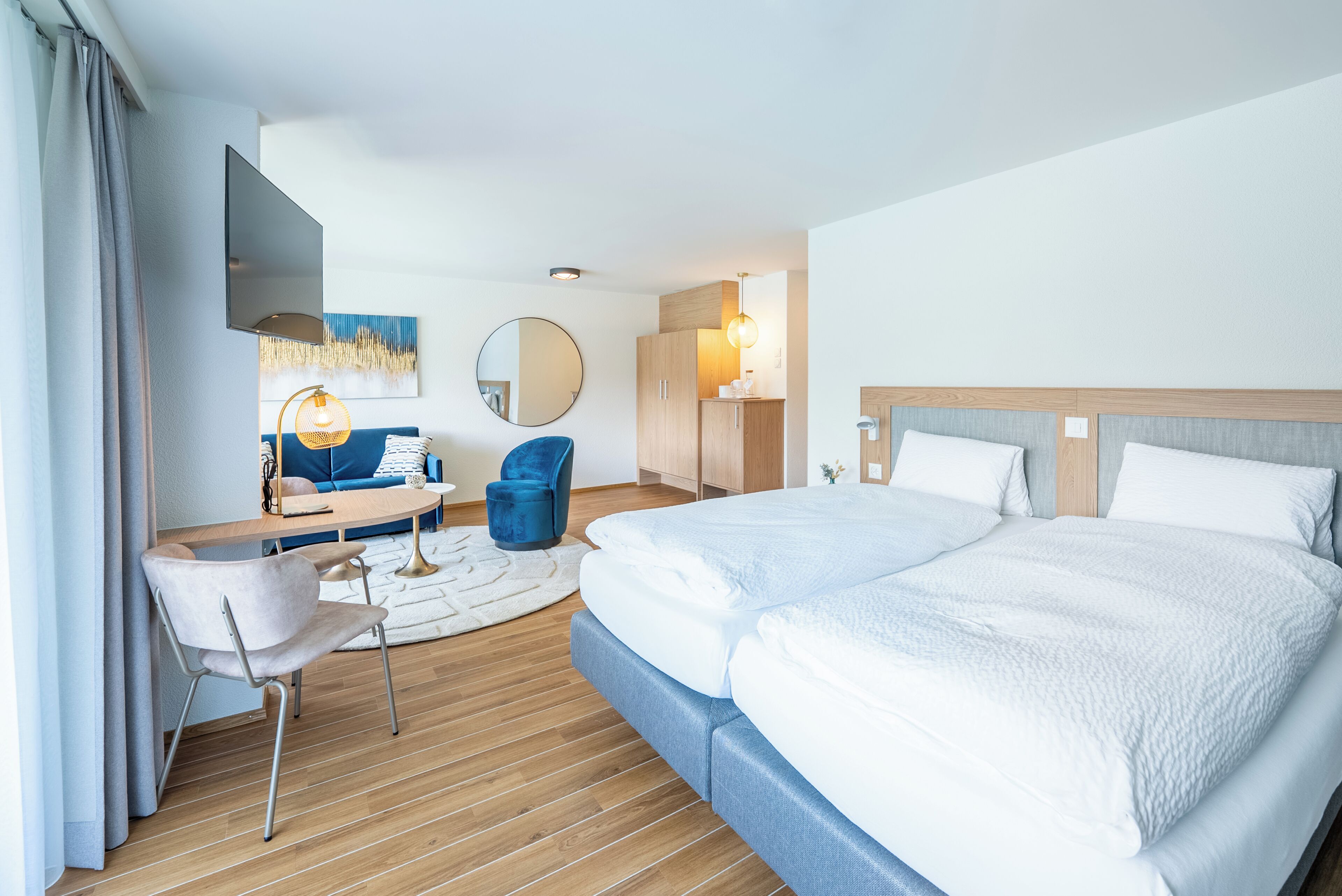Una habitación de hotel con cama, escritorio, silla, televisor y espejo.