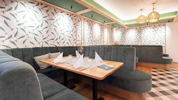 En restaurant med et træbord dækket til spisning, polstrede siddepladser og tapet med mønster.