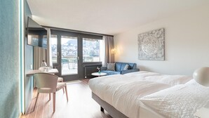 Une chambre d’hôtel moderne dotée d’un grand lit, d’un bureau et d’un coin salon près d’une fenêtre offrant une vue sur la ville.