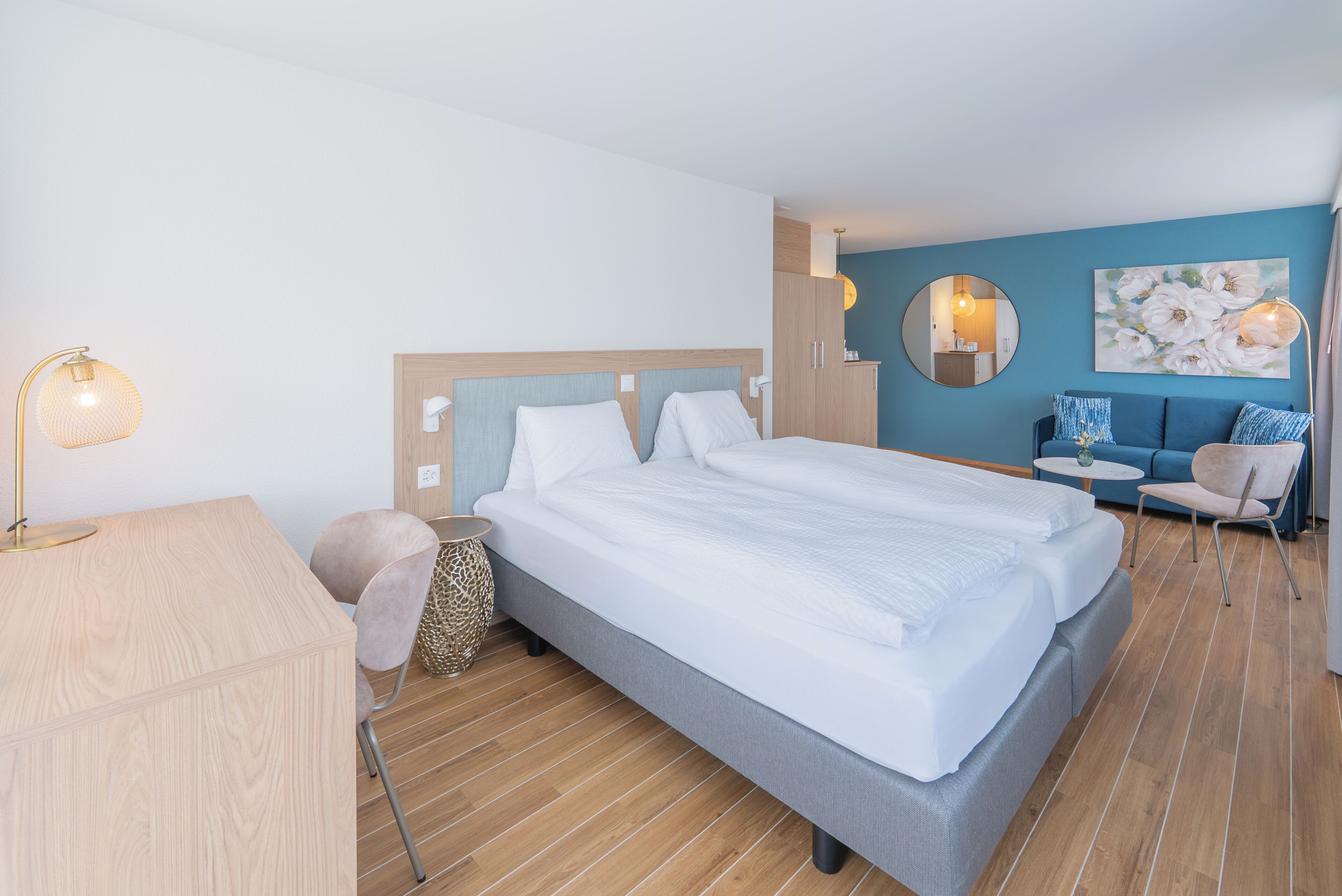 Una habitación de hotel moderna con una cama grande, un escritorio, una silla y una mesita.