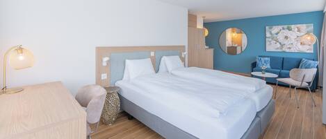Una habitación de hotel moderna con una cama grande, un escritorio, una silla y una mesita.