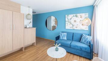 Un salon moderne avec un canapé bleu, un miroir rond et une table basse.