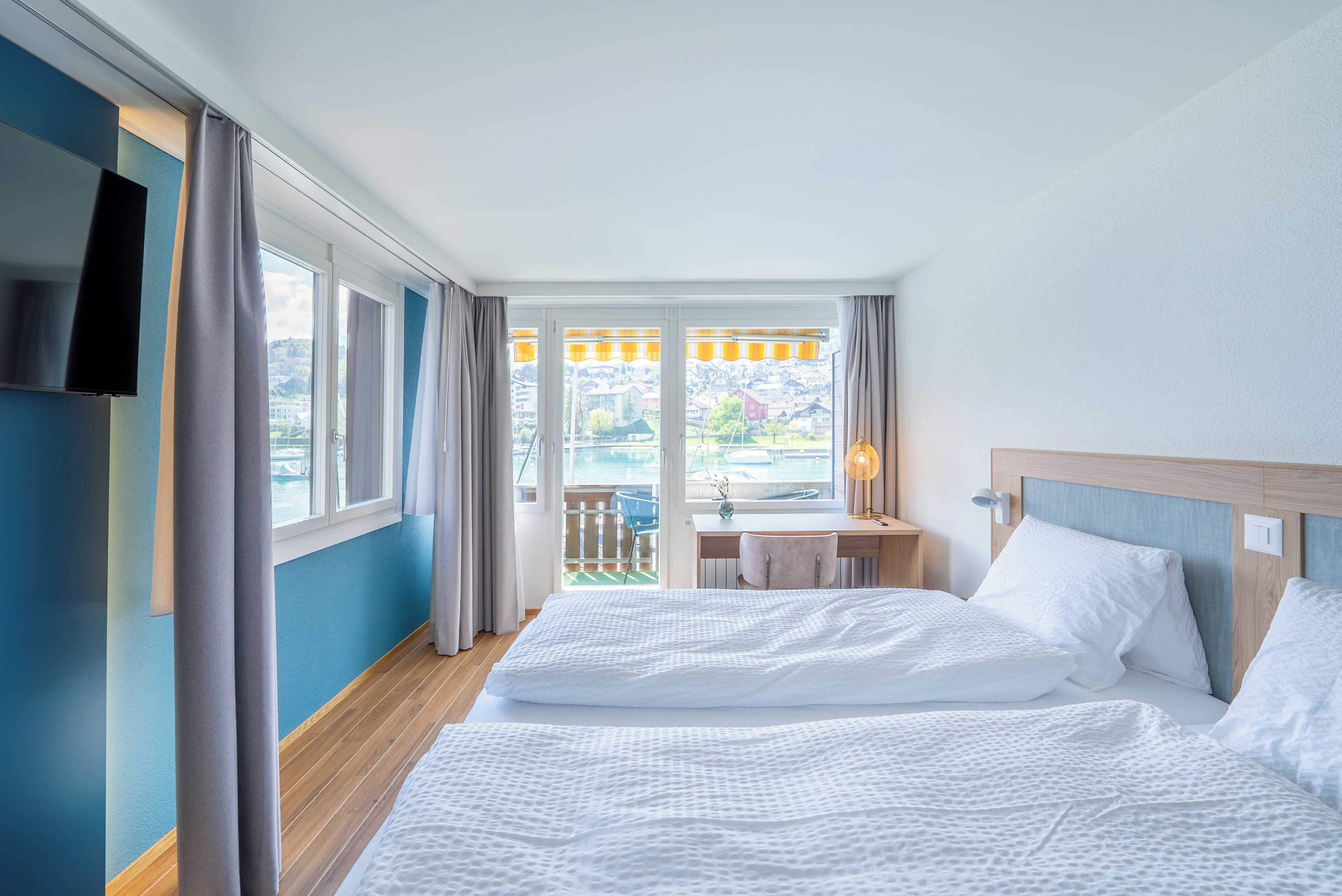 Habitación de hotel con cama, escritorio, televisor y vistas al exterior.