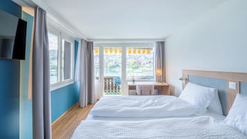 A hotel room with a bed, a desk, a TV, and a view of the outdoors.