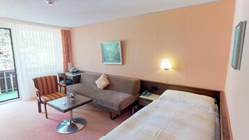 Habitación de hotel con cama, sofá, escritorio, silla, mesita y lámpara.
