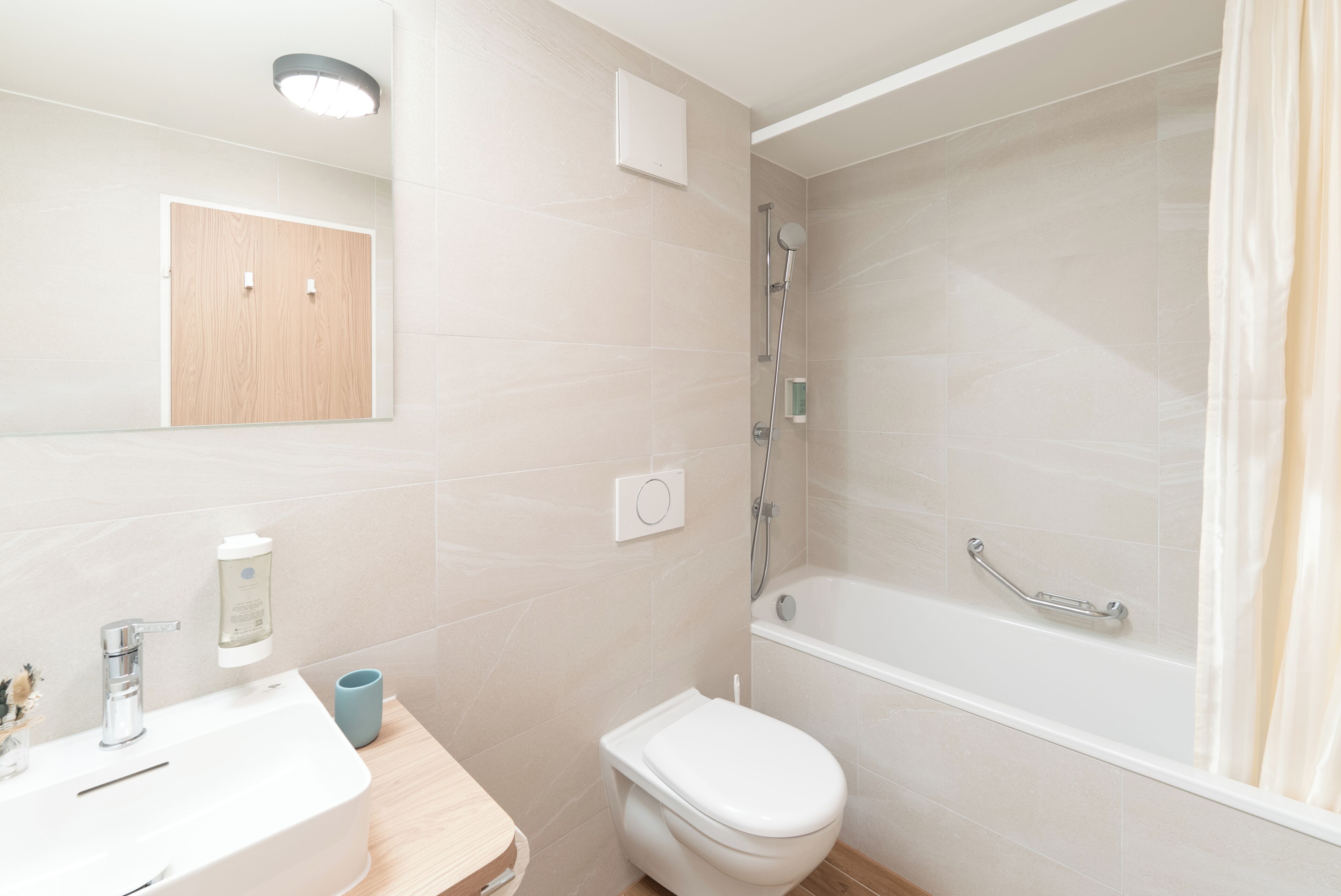 Un baño con lavamanos, inodoro, ducha y espejo.