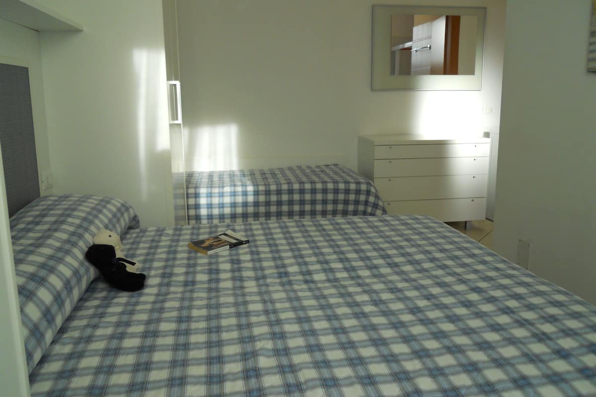 A bedroom with two beds, a dresser, and a mirror on the wall.