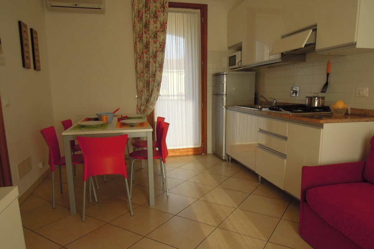 A compact kitchen with a dining area, featuring a refrigerator, microwave, and a sink.