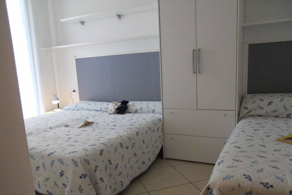 A bedroom with two beds, a wardrobe, and a bedside table with a lamp.