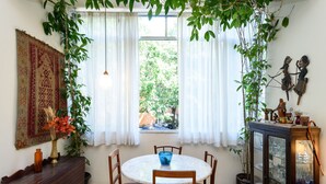 Een eetruimte met een ronde tafel, stoelen, een houten kast en een raam met gordijnen.