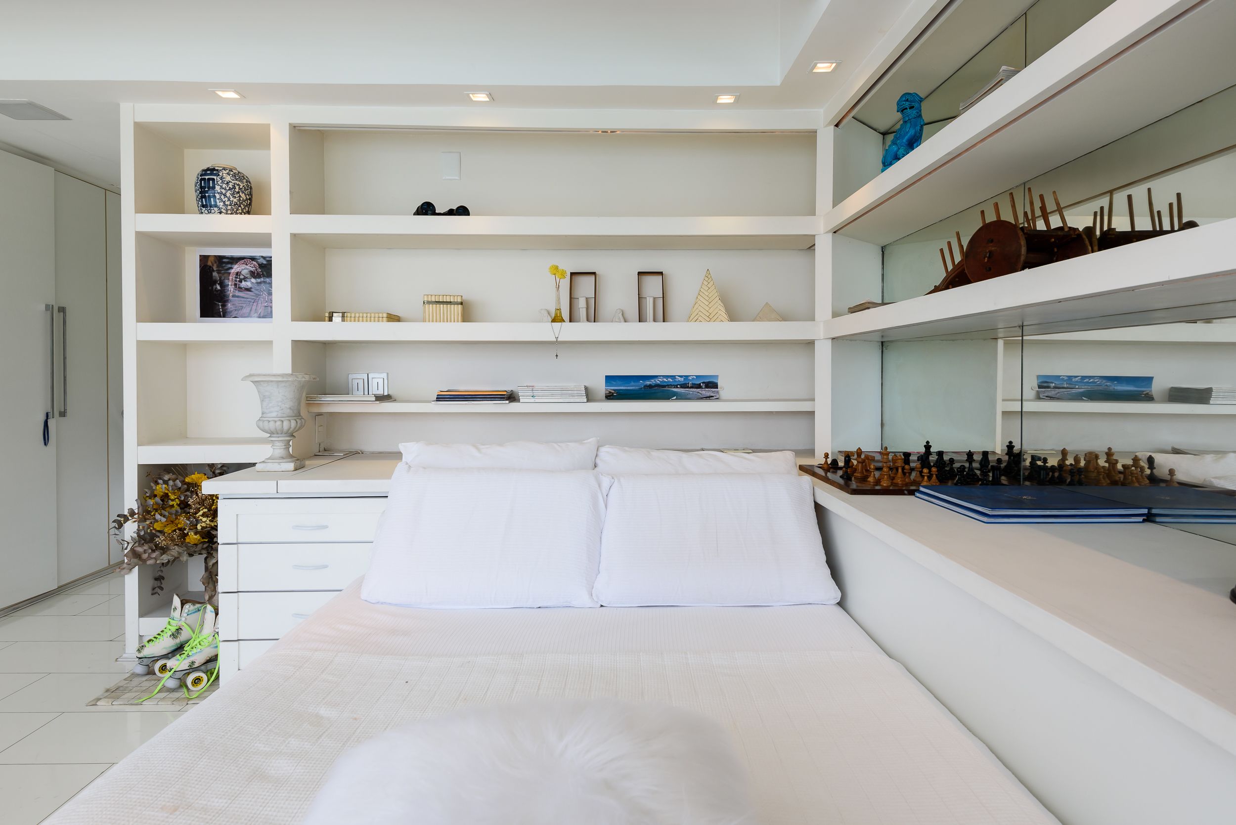 A modern bedroom with a large bed, white bedding, and a chessboard on the nightstand.