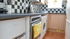 A compact kitchen with a washing machine, a stove, and a microwave.