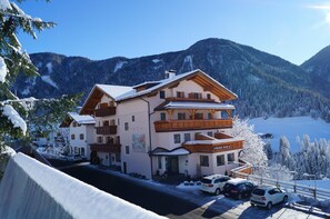 Ein mehrstöckiges Hotel mit einer Seilbahn im Hintergrund, umgeben von schneebedeckten Bergen.