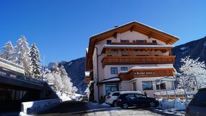 A multi-story building with a wooden facade, a sign reading "Gasthof Lamm," and a parking area with cars. - Gasthof Laurin (Tires)
