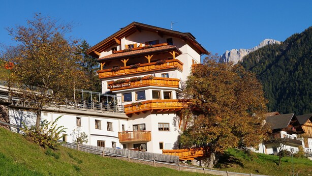 A multi-story hotel with balconies, a mountain backdrop, and a clear sky. - Gasthof Laurin (Tires)