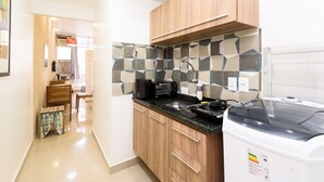 A modern kitchen with wooden cabinets, a black countertop, and a built-in microwave.