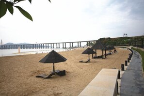 A beach with umbrellas and a pier in the background. - Muhai Resort Apartment (Huidong)