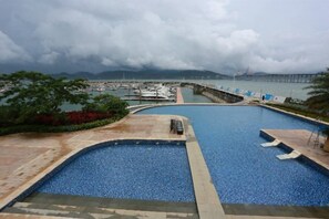 A swimming pool with a view of a marina and a bridge in the distance. - Muhai Resort Apartment (Huidong)