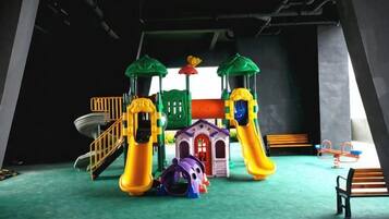 A children's play area with slides, a climbing structure, and a small building.