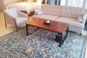 Quarto de hotel com cama, sofá, poltrona e mesa de centro.