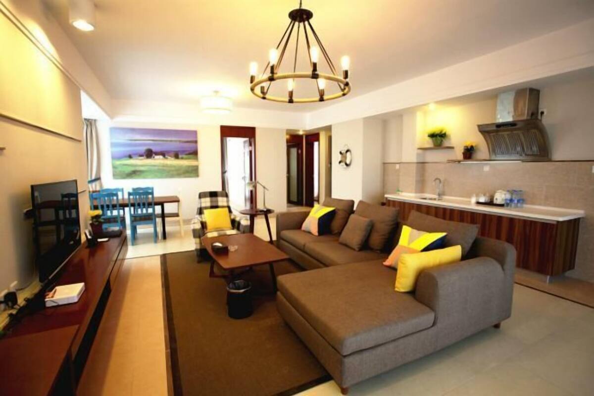 Uma sala de estar moderna com sofá, mesa de centro, televisão e uma área de jantar com cadeiras e mesa.