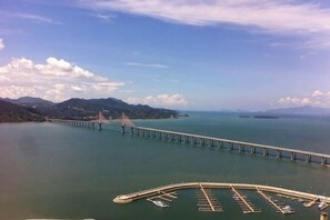 A long bridge over a body of water with a parking area in the foreground. - Muhai Resort Apartment (Huidong)