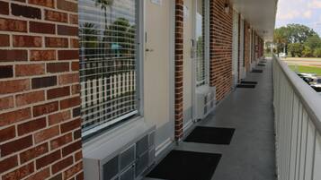 A brick building with a covered porch, numbered doors, and a clear view of the street.
