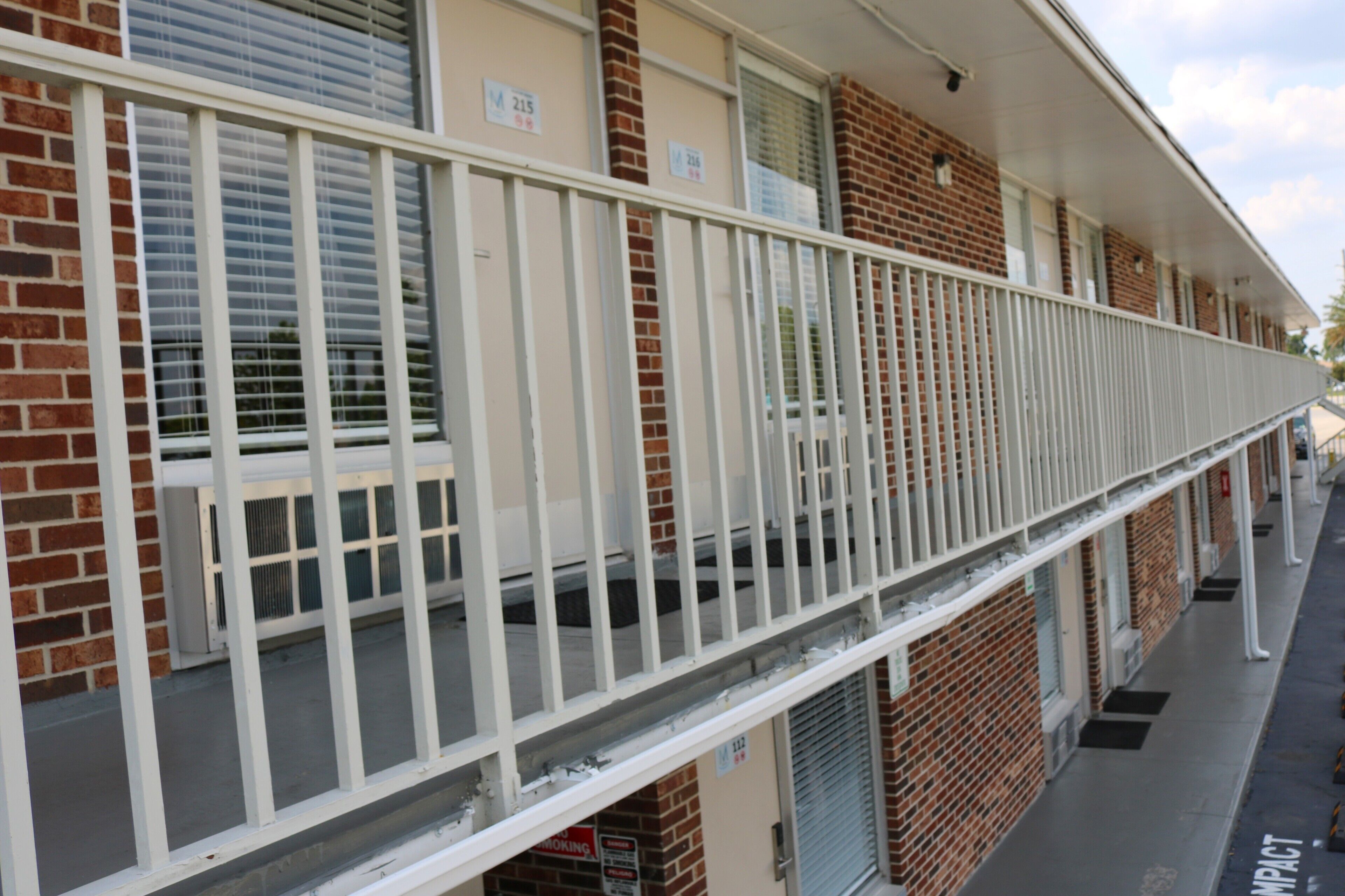 Un immeuble à plusieurs étages, doté d’une balustrade blanche, d’une façade en briques et de nombreuses fenêtres.