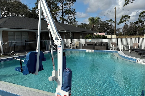 Een buitenzwembad, parasols bij het zwembad en ligstoelen