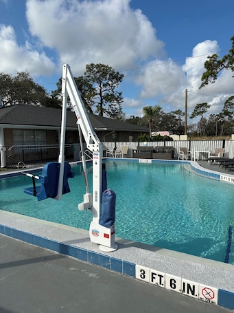 Una piscina al aire libre, sombrillas, sillones reclinables de piscina