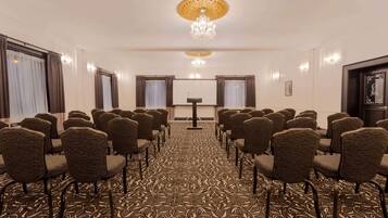 Un salón de conferencias con filas de sillas, un atril y una alfombra estampada.
