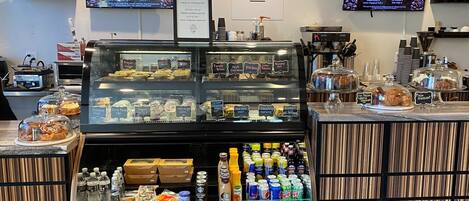 Een café met een vitrine vol gebak en een assortiment flessen drank.