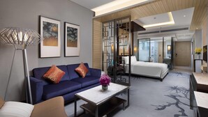 A modern hotel room with a sofa, a coffee table, a lamp, and artwork on the wall. - Wyndham LanZhou HaiYue (Lanzhou)
