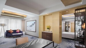 A hotel room with a bed, a desk, a sofa, a coffee table, a cabinet, and a large window with curtains. - Wyndham LanZhou HaiYue (Lanzhou)