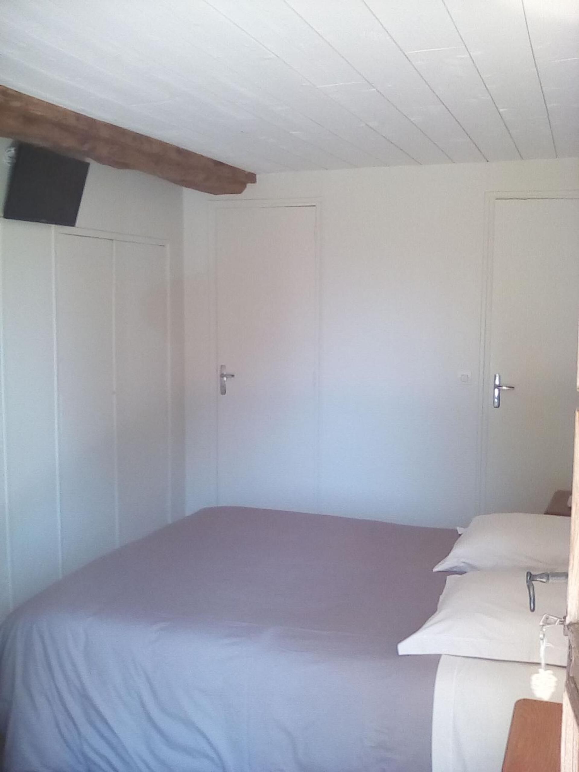 Une chambre à coucher avec un lit, deux portes et une poutre en bois au plafond.