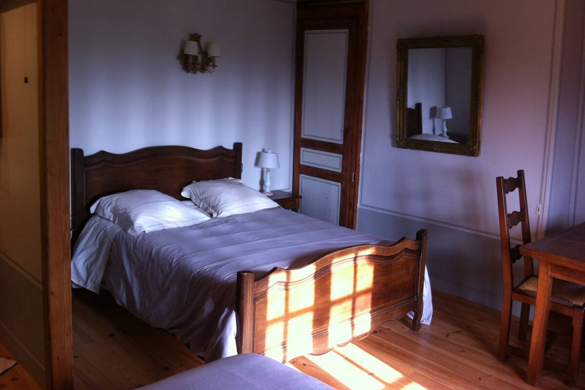 Un dormitorio con una cama de madera, una mesita de noche, una silla y un espejo en la pared.