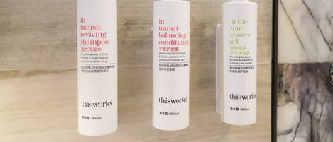 Three bottles of shampoo, conditioner, and shower gel with text in multiple languages.