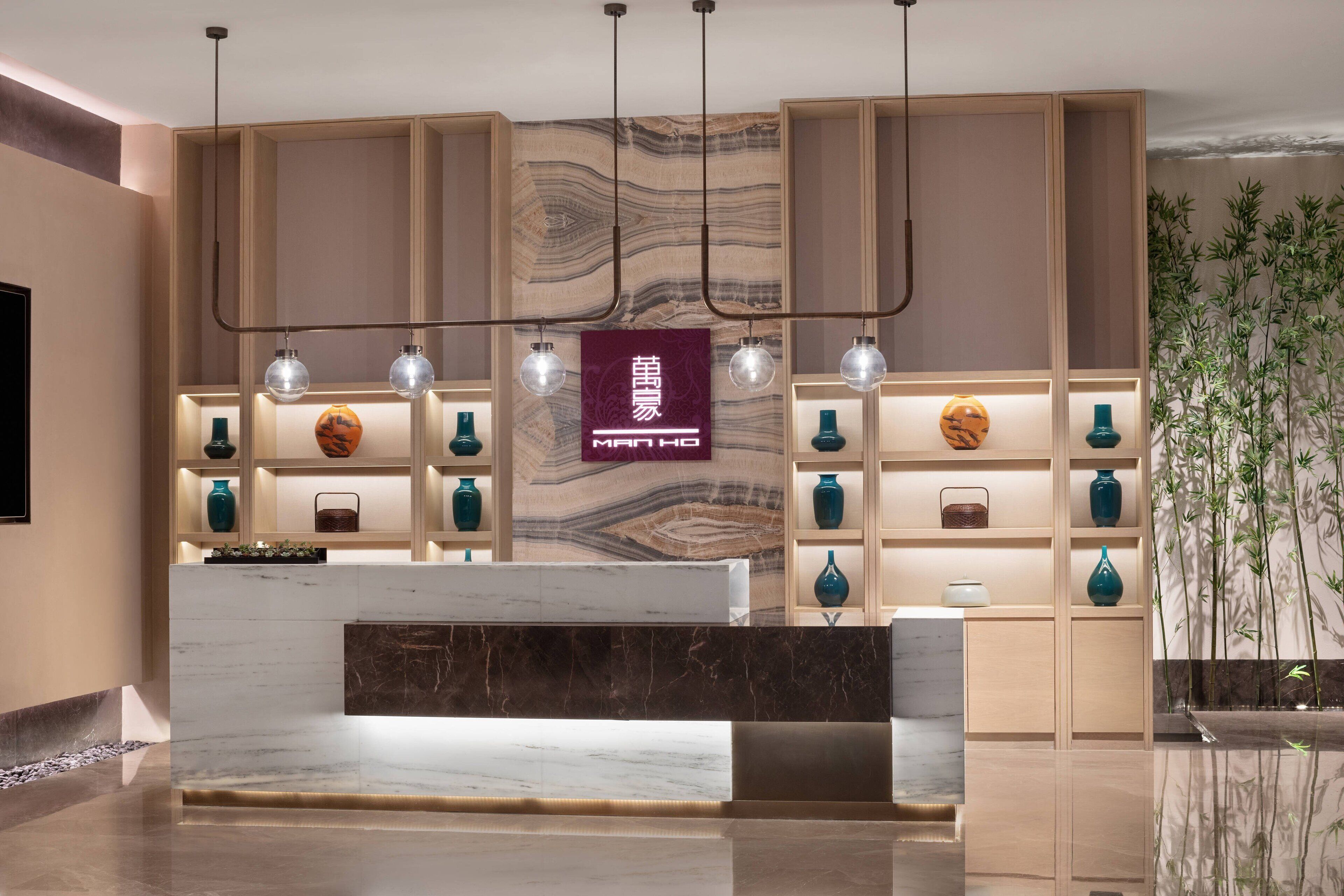 A reception area with a marble counter, shelves with decorative items, and a wall with a marbled pattern.