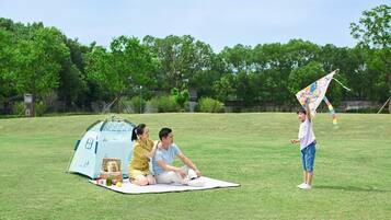 Enjoy a family-friendly picnic in a serene outdoor setting surrounded by lush greenery.