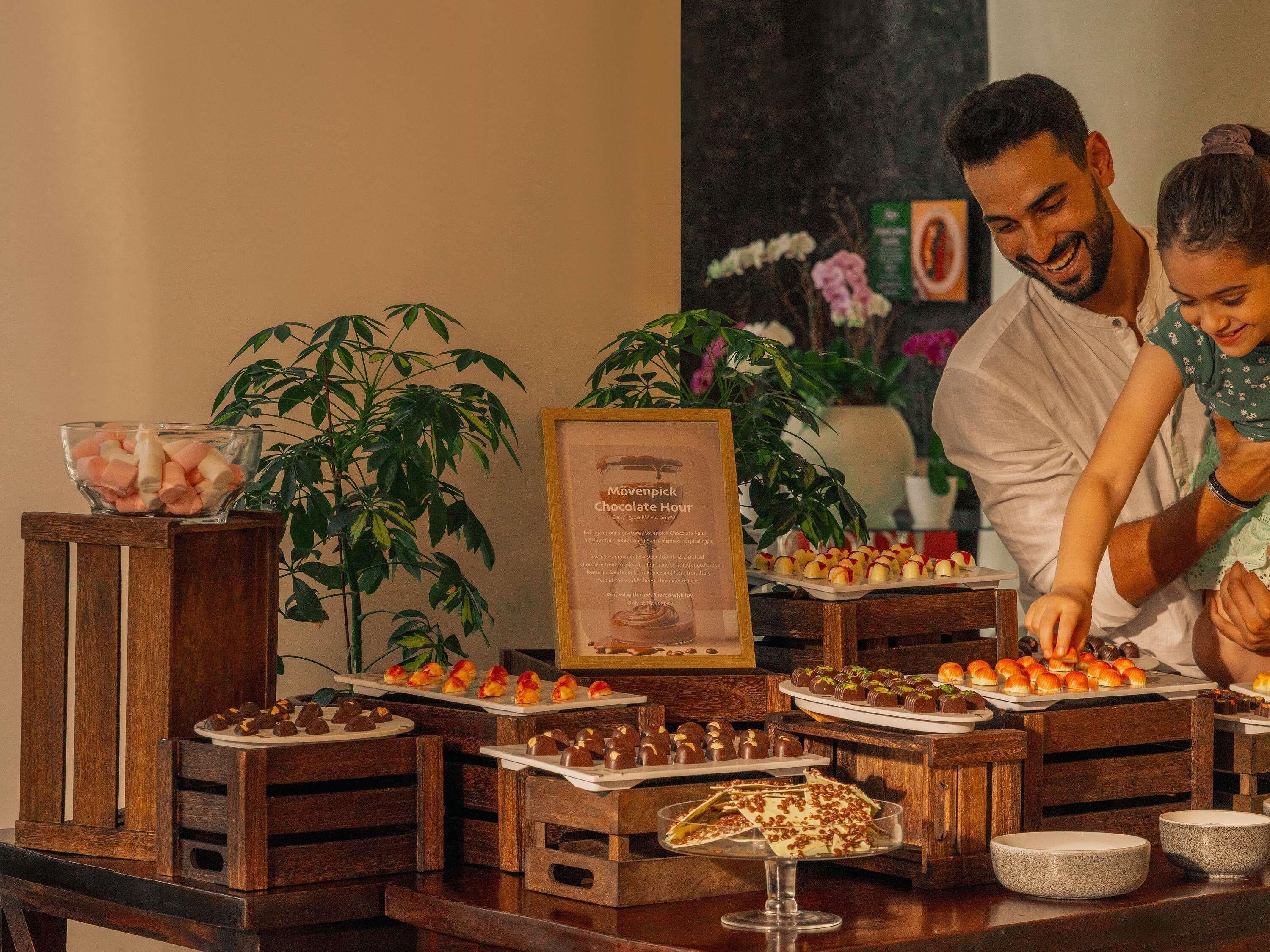 A buffet table with various desserts and a sign indicating a chocolate hour event.