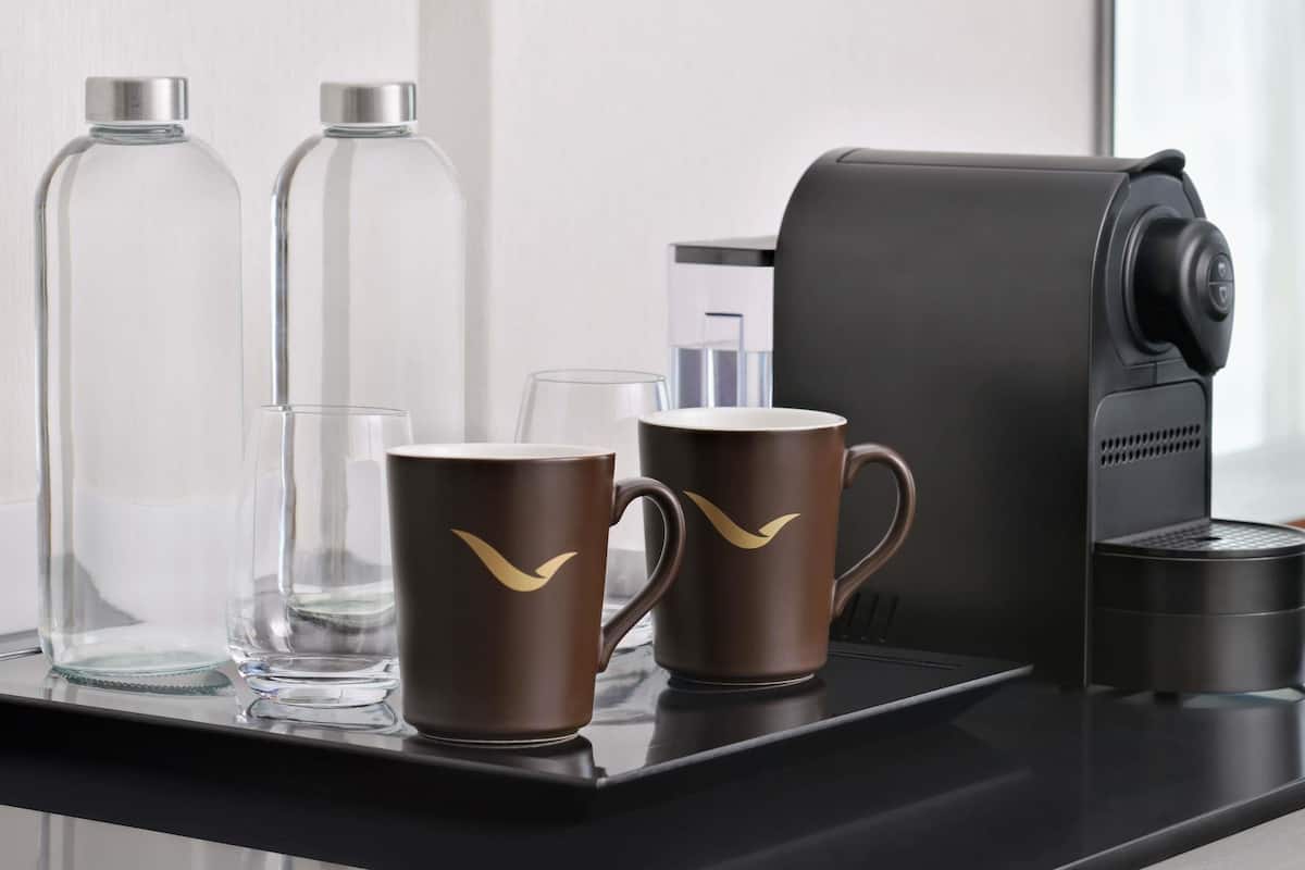Una cafetera, dos tazas de café y dos botellas de vidrio sobre una bandeja.